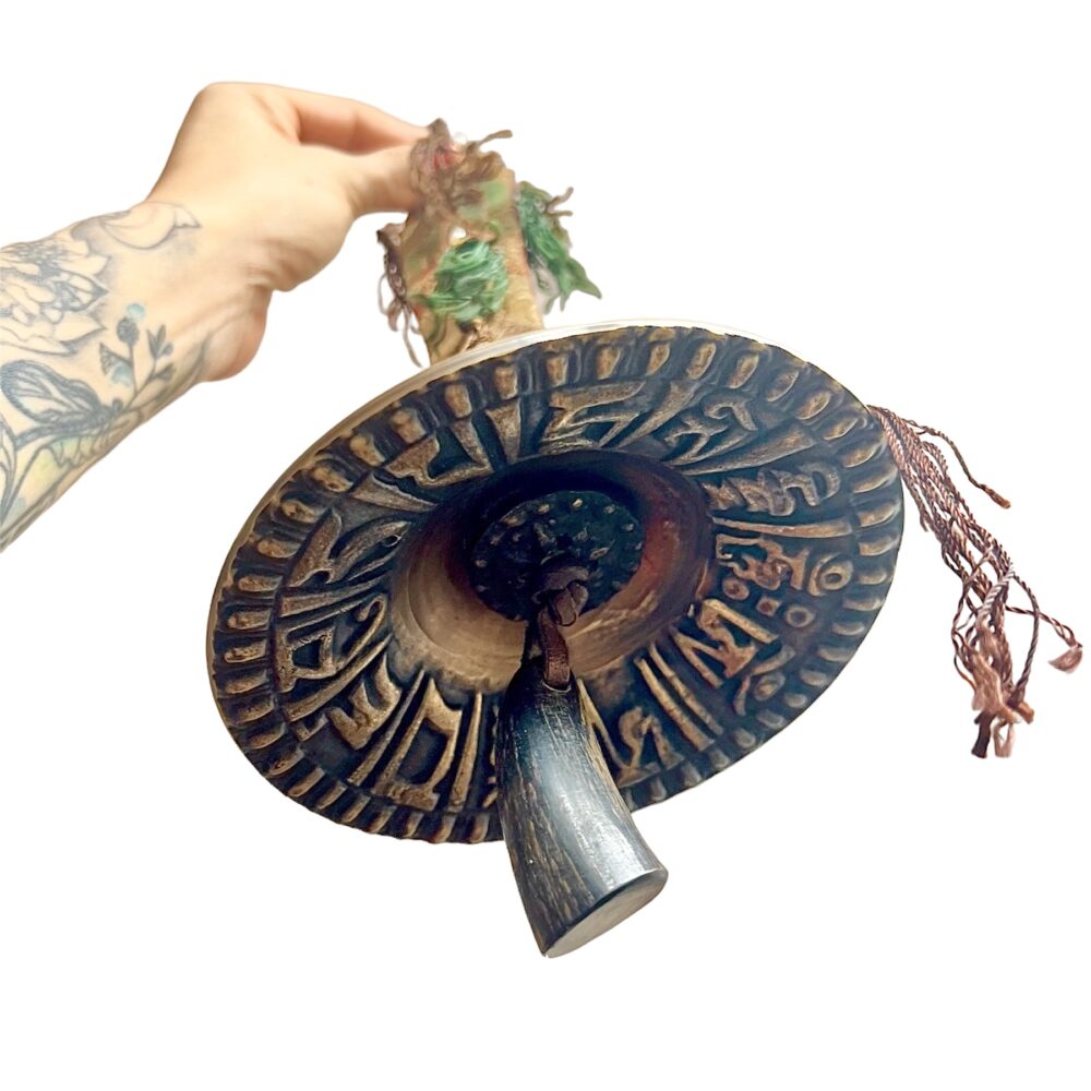 Campana Tibetana Para Ceremonias sostenida en una mano con fondo blanco